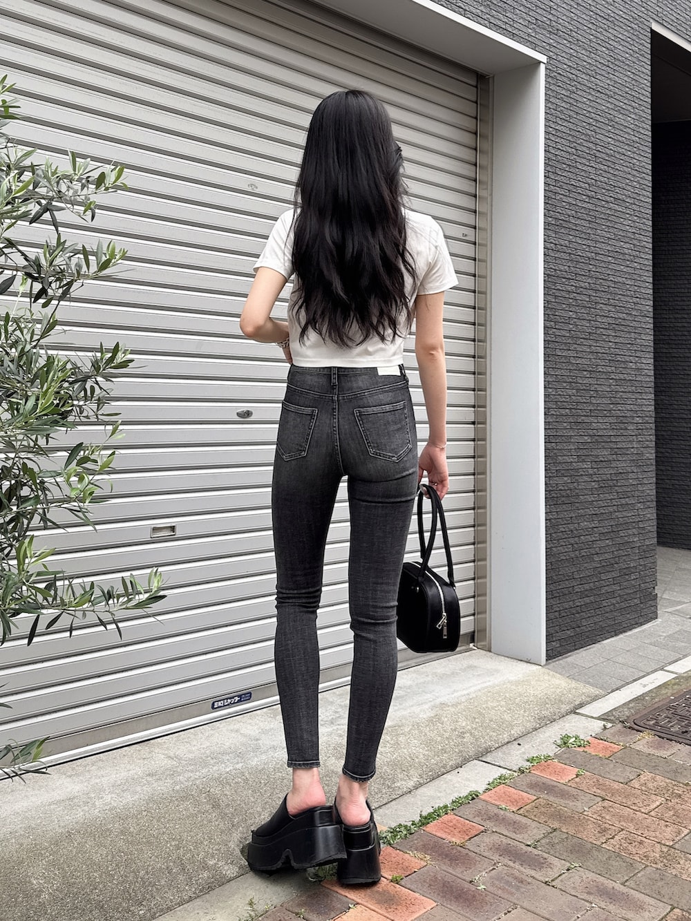 ホワイト系のTシャツ/カットソー、ブラック系のデニムパンツ、ブラック系のボストンバッグを着用したレディースの夏コーディネートの3枚目の写真