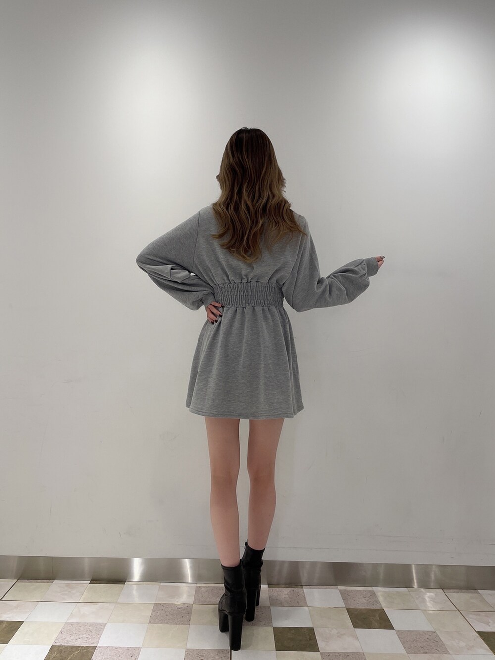 グレー系のワンピース、ブラック系のデニムパンツ、ブラック系のブーツを着用したレディースの冬コーディネートの3枚目の写真