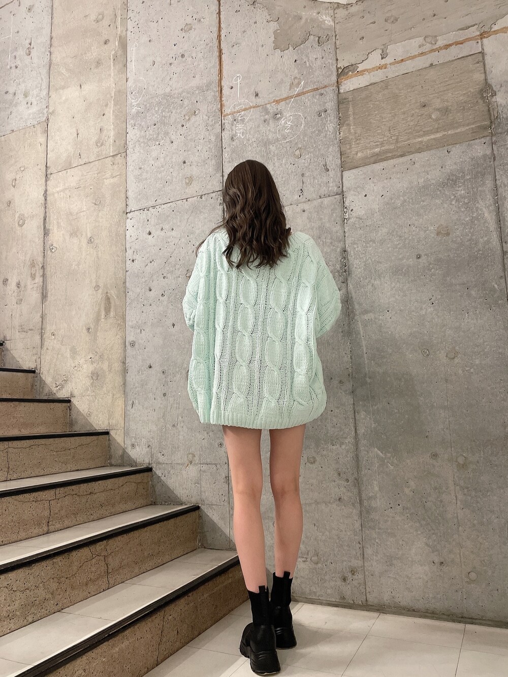 グリーン系のカーディガン/ボレロ、ホワイト系のTシャツ/カットソー、ブルー系のデニムスカートを着用したレディースの冬コーディネートの3枚目の写真