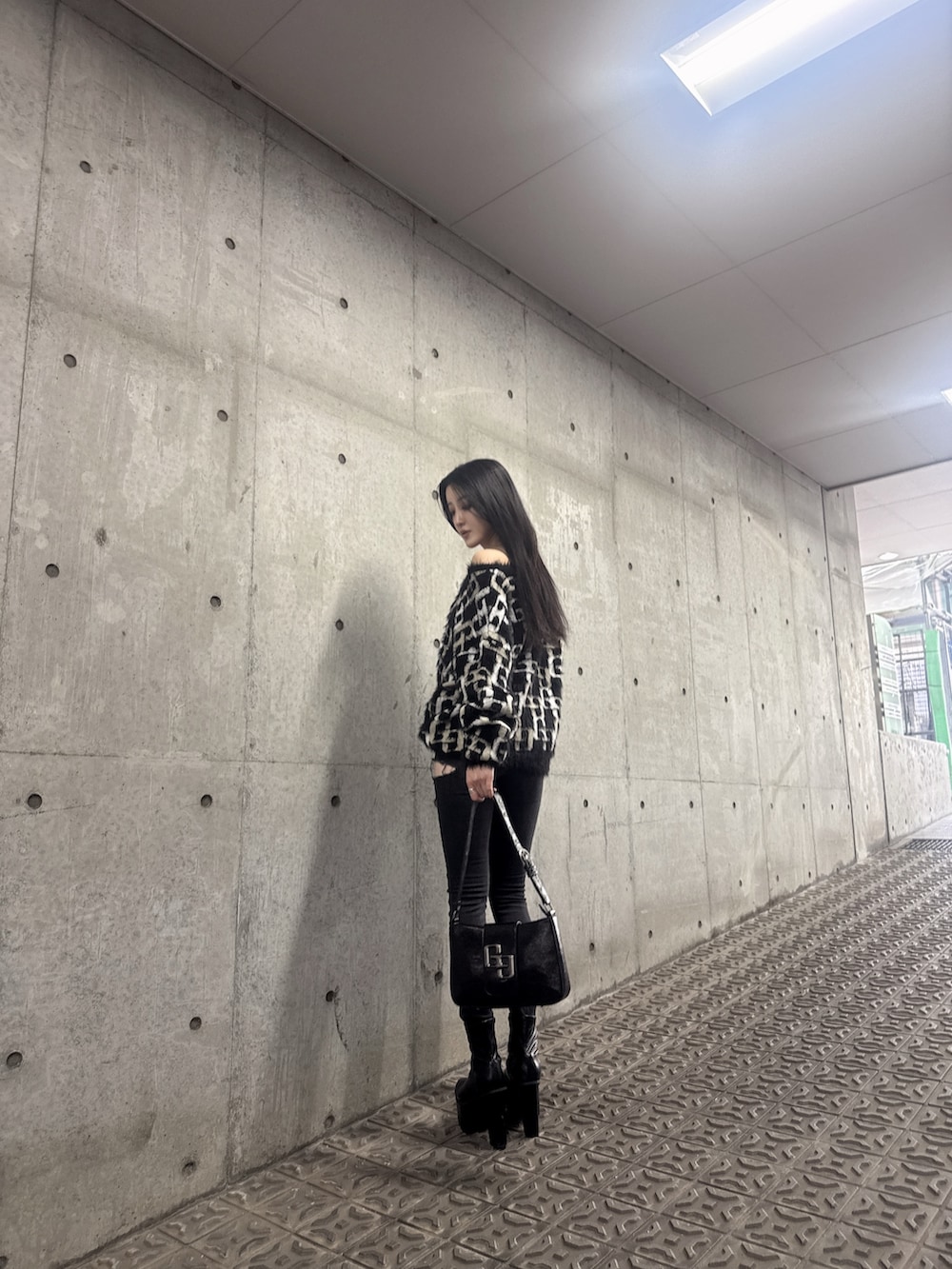 ブラック系のニット/セーター、ブラック系のデニムパンツ、ブラック系のブーツを着用したレディースの冬コーディネートの2枚目の写真