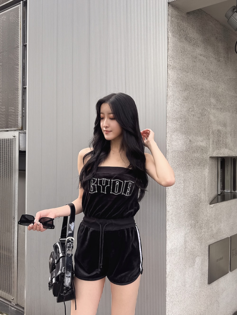 ブラック系のワンピース、ブラック系のハンドバッグ、ブラック系のサンダルを着用したレディースの夏コーディネートの2枚目の写真