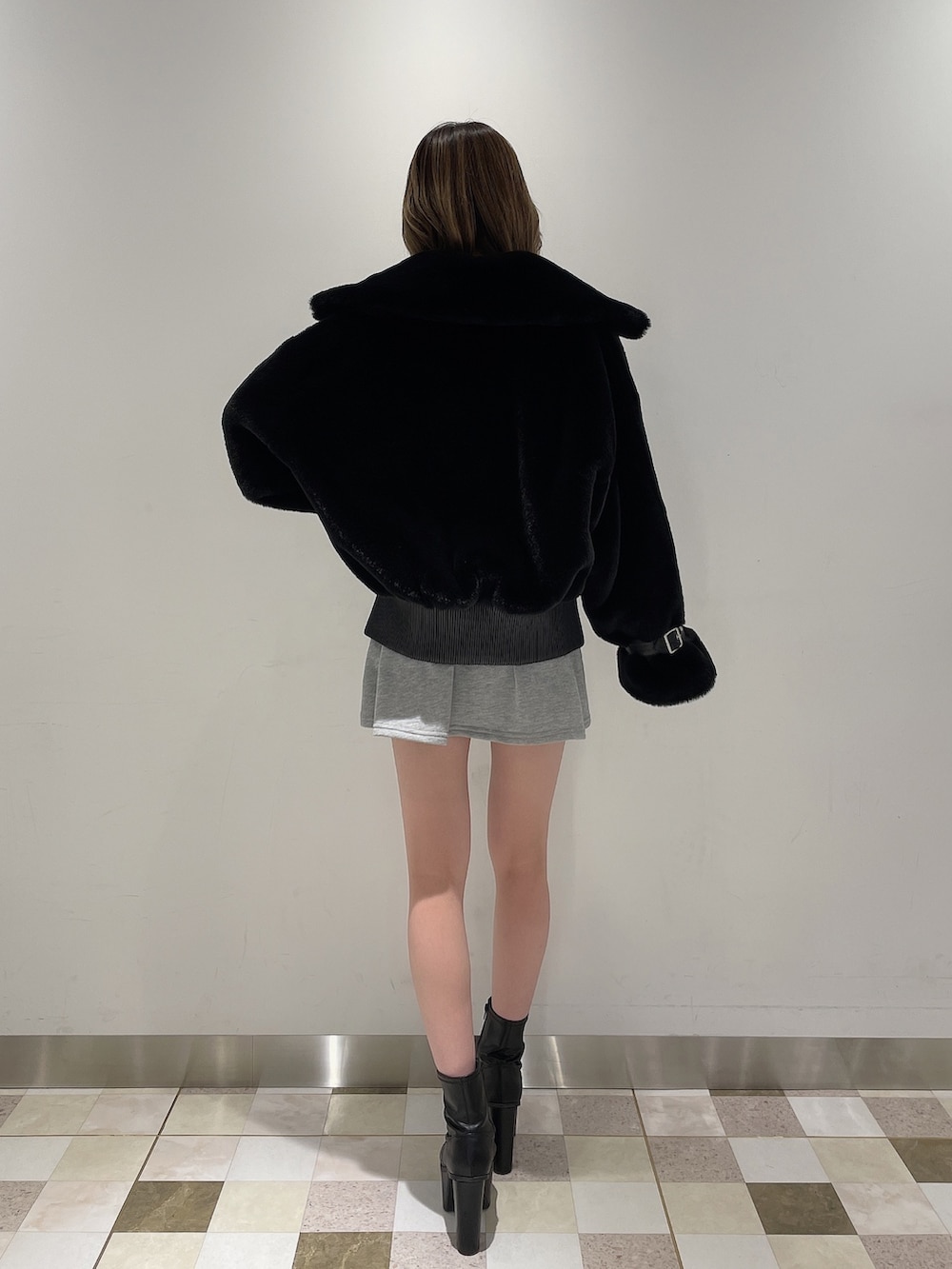 グレー系のワンピース、ブラック系のブーツ、ブラック系のブルゾンを着用したレディースの冬コーディネートの3枚目の写真