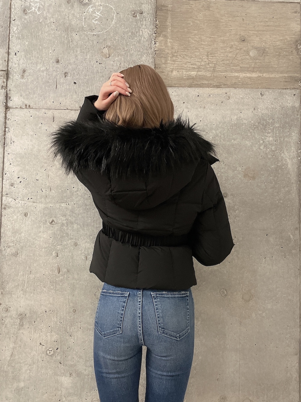 ブラック系のダウンジャケット/コート、その他のニット/セーター、ブルー系のデニムパンツを着用したレディースの秋コーディネートの4枚目の写真