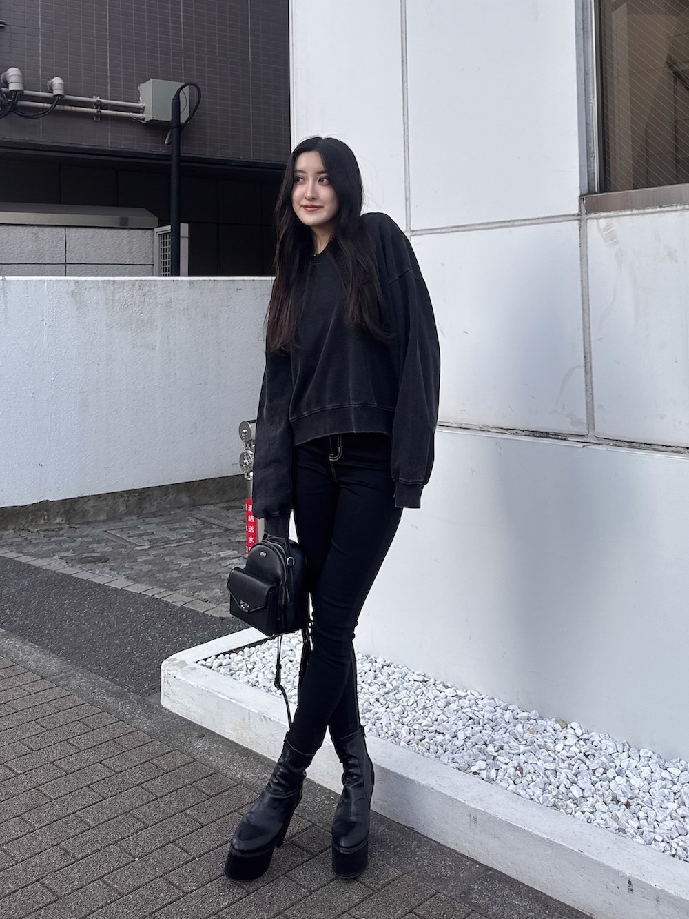 ブラック系のスウェット、ブラック系のデニムパンツ、ブラック系のブーツを着用したレディースの冬コーディネートの3枚目の写真