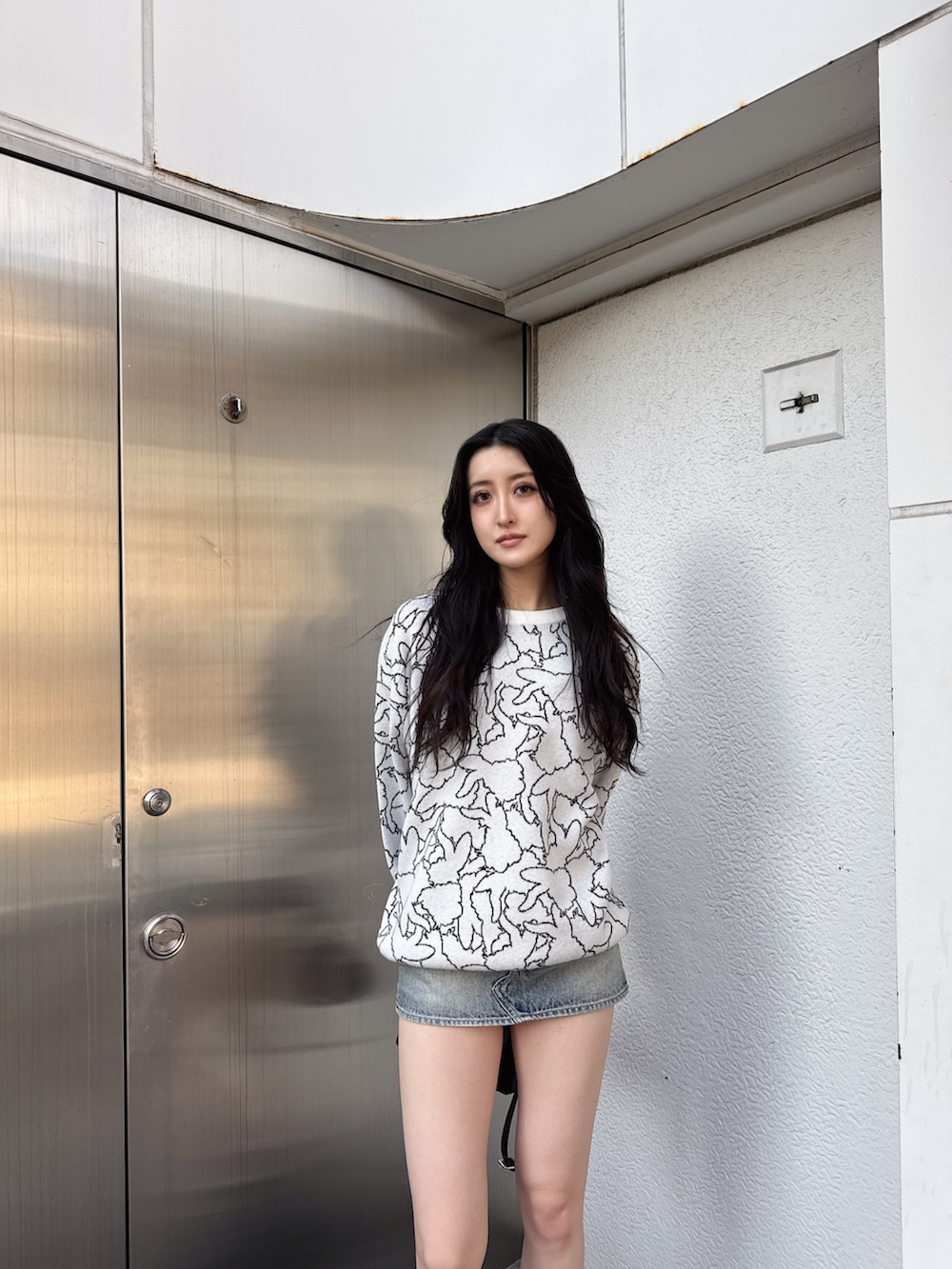 ホワイト系のニット/セーター、ブルー系のデニムスカート、ブラック系のブーツを着用したレディースの冬コーディネートの4枚目の写真