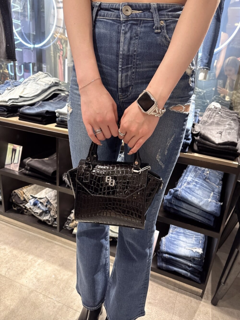 ブラック系のハンドバッグ、ブラック系のニット/セーター、ブルー系のデニムパンツを着用したレディースの夏コーディネートの7枚目の写真