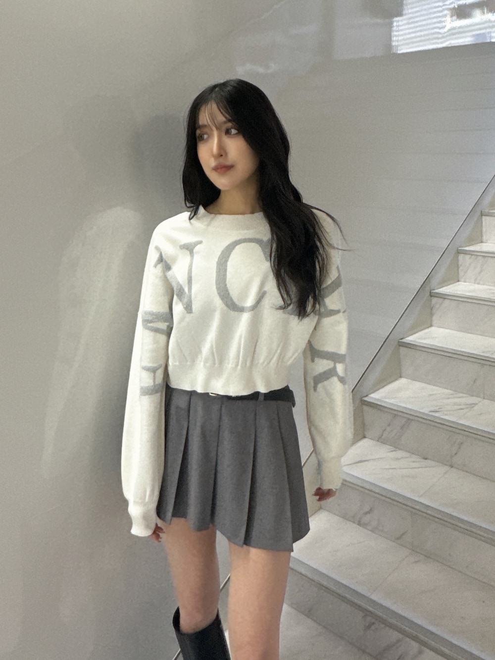 ホワイト系のニット/セーター、グレー系のスカート、ブラック系のブーツを着用したレディースの冬コーディネートの4枚目の写真