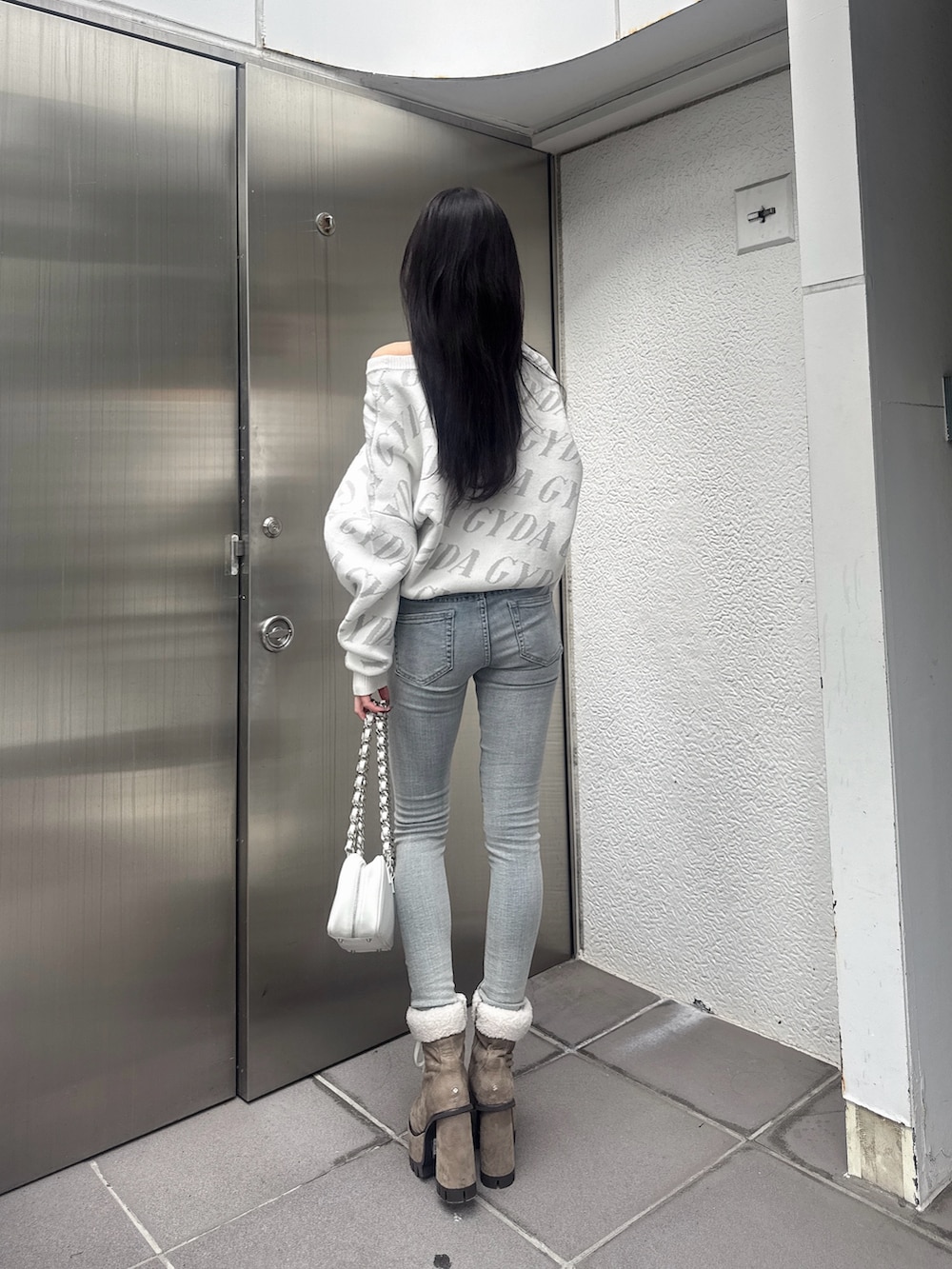 ホワイト系のニット/セーター、ホワイト系のショルダーバッグ、ブルー系のデニムパンツを着用したレディースの秋コーディネートの3枚目の写真