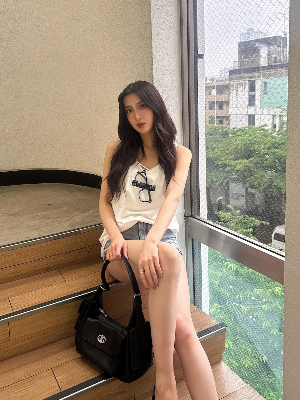 ホワイト系のワンピース、ブルー系のデニムパンツ、ブラック系のハンドバッグを着用したレディースの夏コーディネートの3枚目の写真