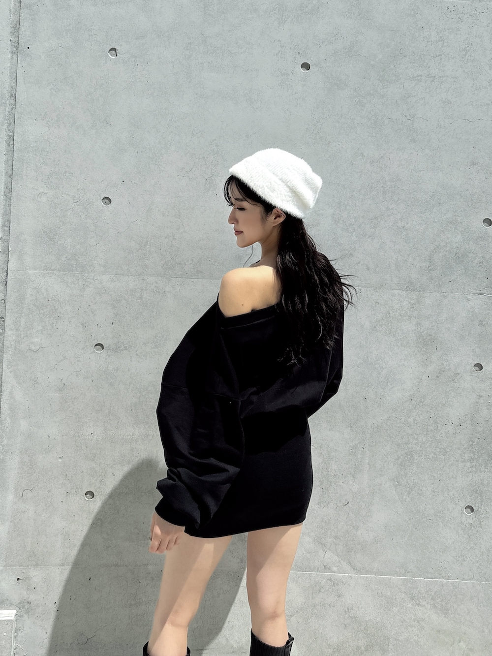ブラック系のワンピース、ブラック系のブーツ、ホワイト系のニットキャップ/ビーニーを着用したレディースの秋コーディネートの4枚目の写真