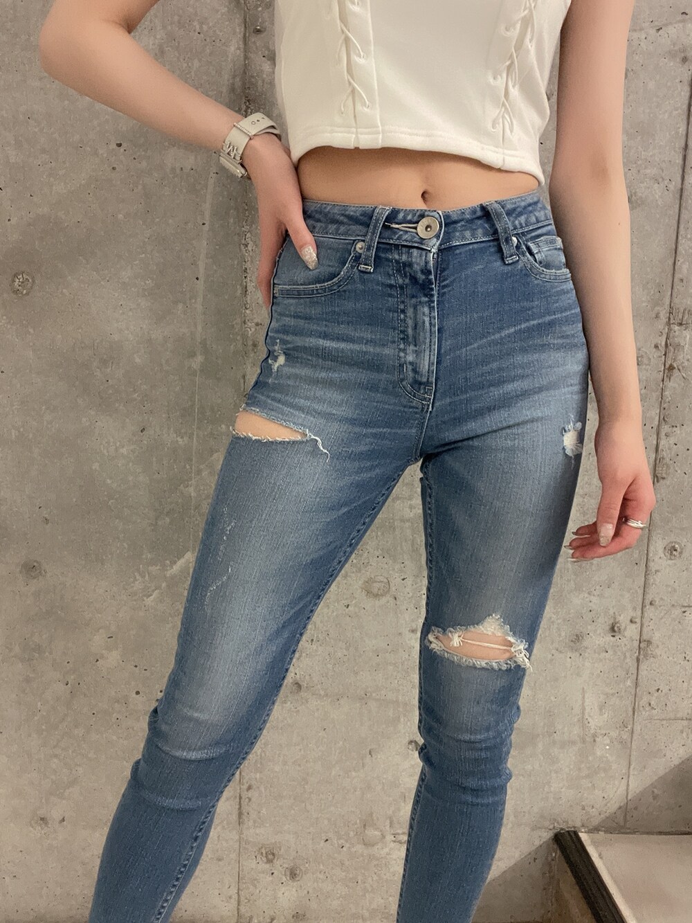 ブルー系のデニムパンツ、ホワイト系のチューブトップ、ホワイト系のパンプスを着用したレディースの春コーディネートの5枚目の写真