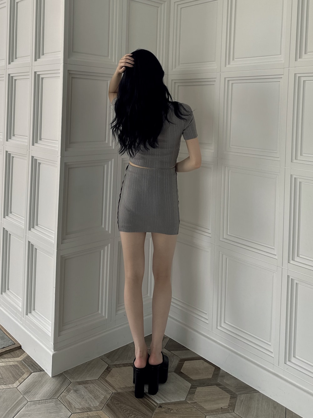 グレー系のニット/セーター、グレー系のスカート、ブラック系のサンダルを着用したレディースの夏コーディネートの3枚目の写真