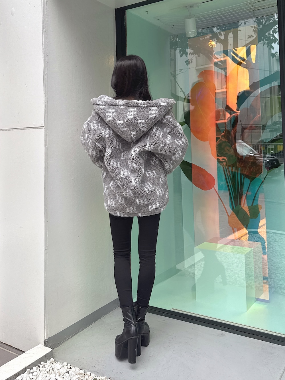 グレー系のブルゾン、ホワイト系のニット/セーター、ブラック系のデニムパンツを着用したレディースの秋コーディネートの2枚目の写真