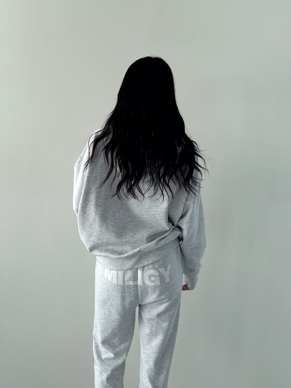 グレー系のパーカー、グレー系のスウェットパンツ、ホワイト系のパンプスを着用したレディースの秋コーディネートの5枚目の写真