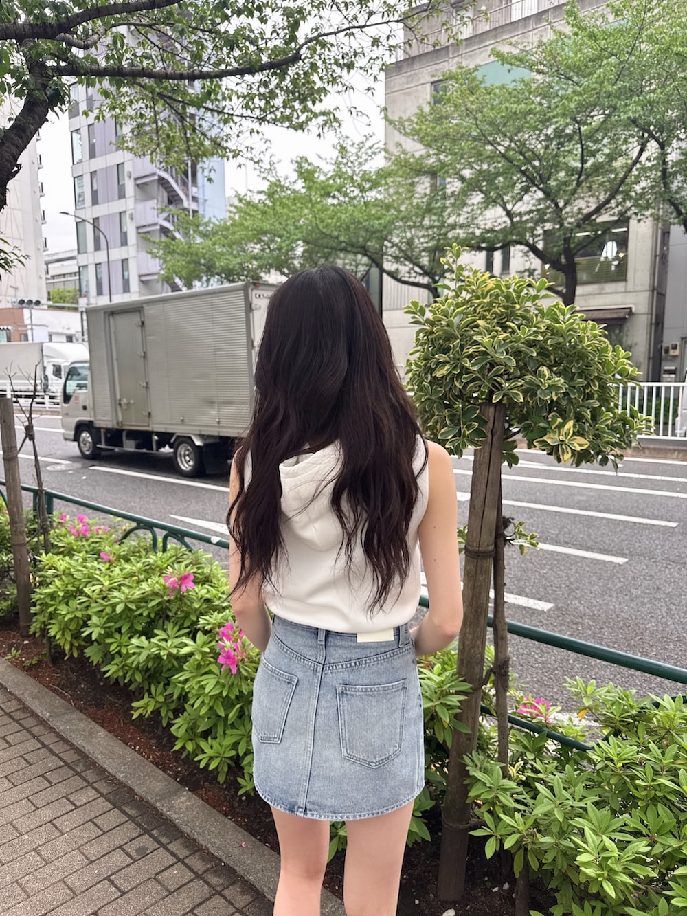 ホワイト系のパーカー、ブルー系のデニムスカート、ブラック系のサンダルを着用したレディースの春コーディネートの3枚目の写真