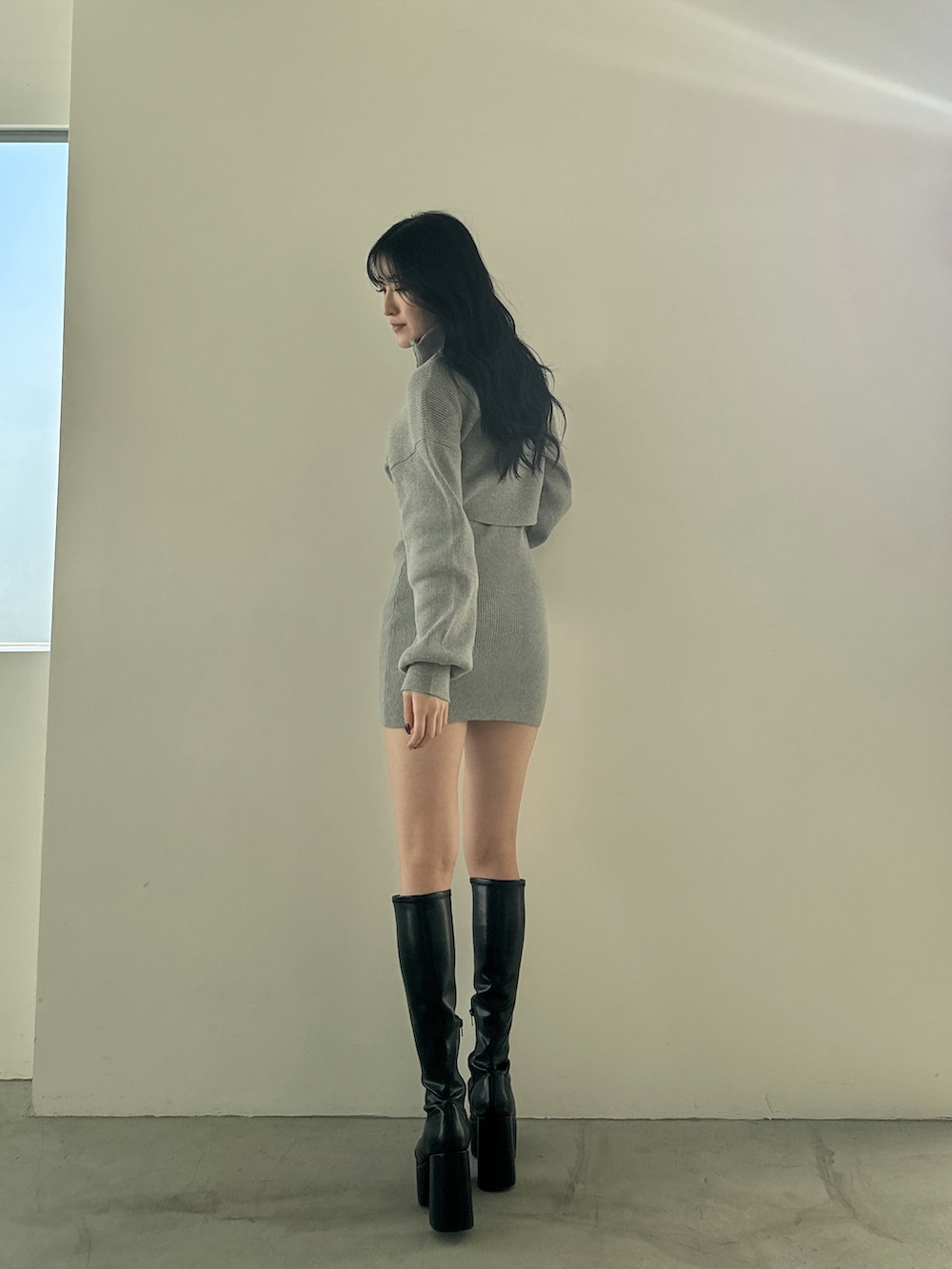 グレー系のワンピース、ブラック系のブーツを着用したレディースの冬コーディネートの2枚目の写真