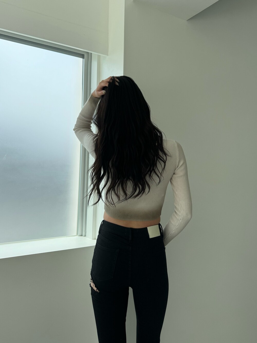 ホワイト系のニット/セーター、ブラック系のデニムパンツ、ブラック系のブーツを着用したレディースの秋コーディネートの4枚目の写真