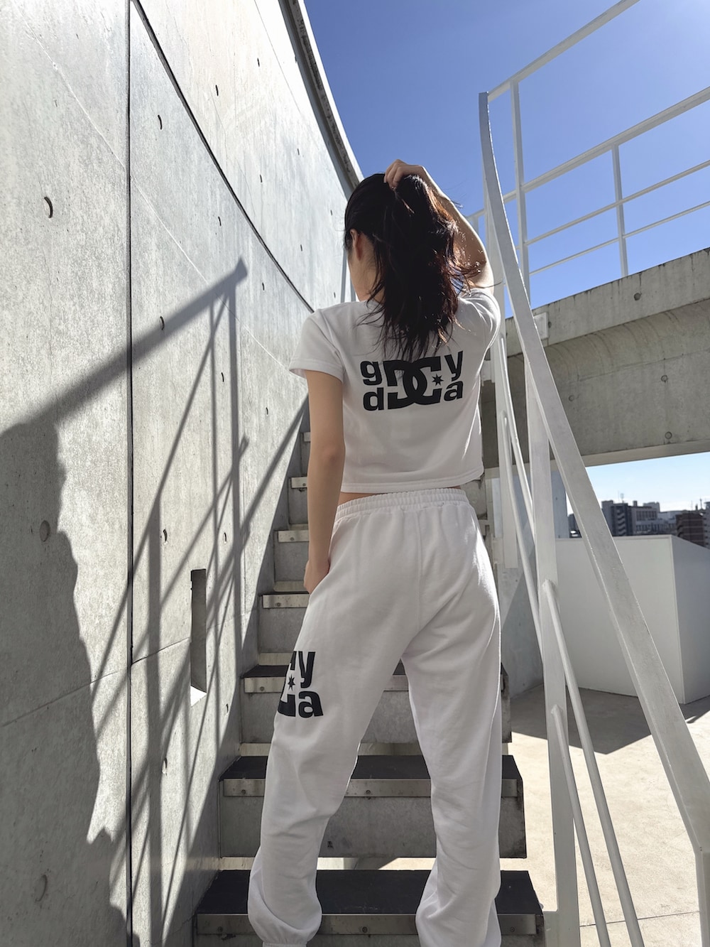 ホワイト系のTシャツ/カットソー、ホワイト系のスウェットパンツ、ブラック系のサンダルを着用したレディースの春コーディネートの3枚目の写真