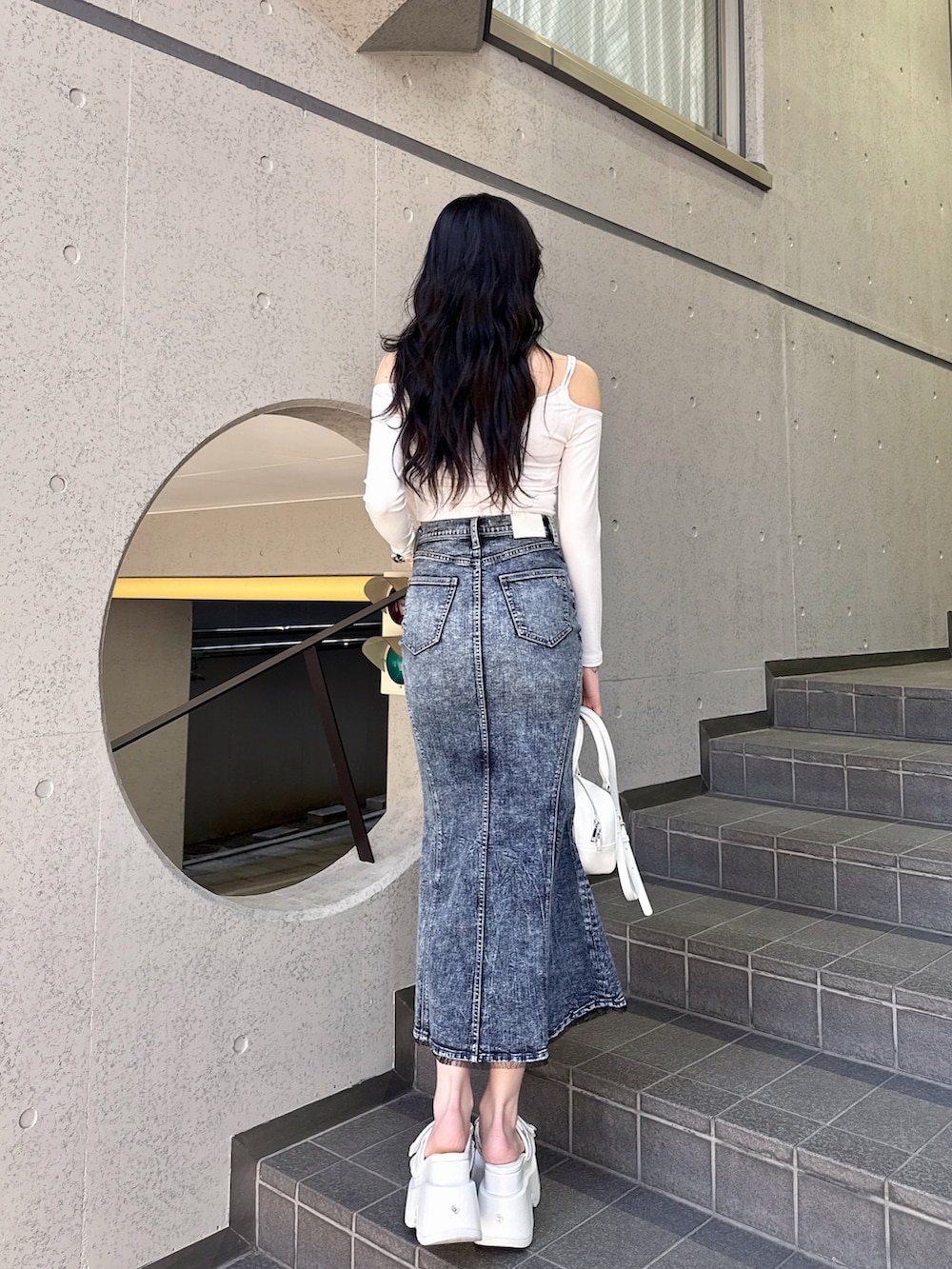 ホワイト系のTシャツ/カットソー、ブルー系のデニムスカート、ホワイト系のハンドバッグを着用したレディースの冬コーディネートの3枚目の写真