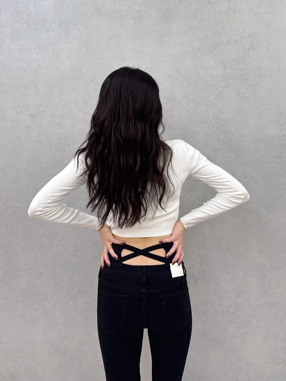 ホワイト系のニット/セーター、ブラック系のデニムパンツ、ホワイト系のパンプスを着用したレディースの冬コーディネートの4枚目の写真