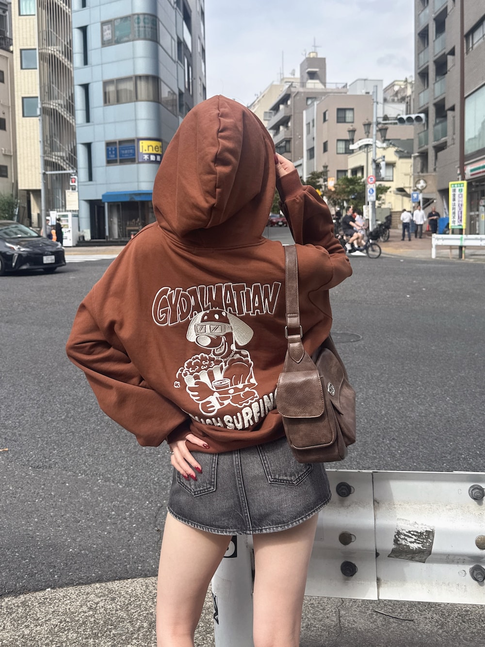 ブラウン系のパーカー、ブラウン系のハンドバッグ、ブラック系のデニムスカートを着用したレディースの秋コーディネートの4枚目の写真