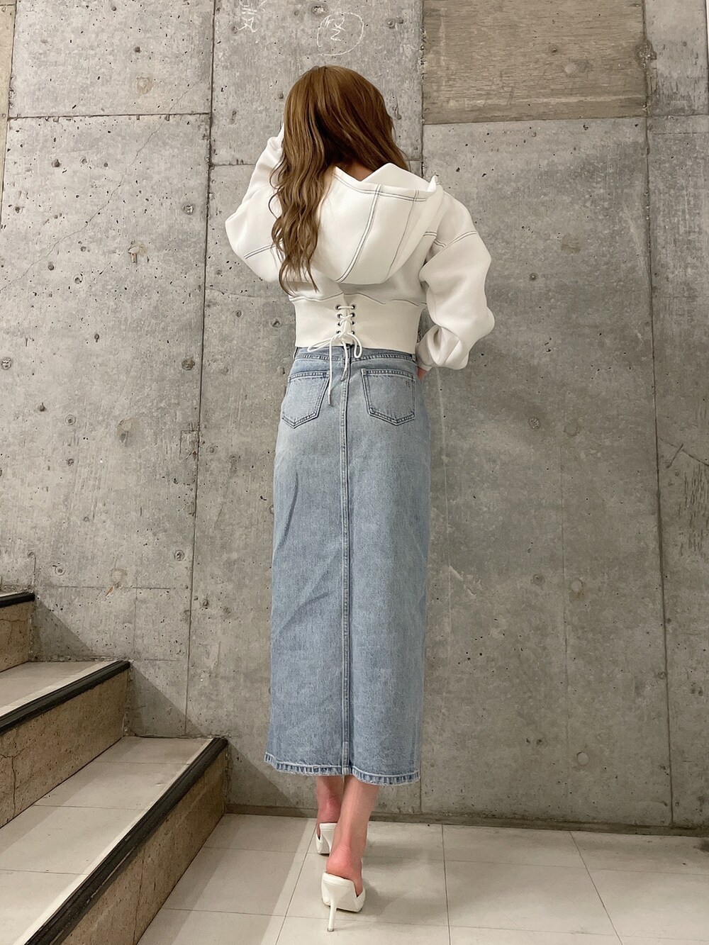 ホワイト系のパーカー、ブルー系のデニムスカート、ホワイト系のパンプスを着用したレディースの冬コーディネートの3枚目の写真