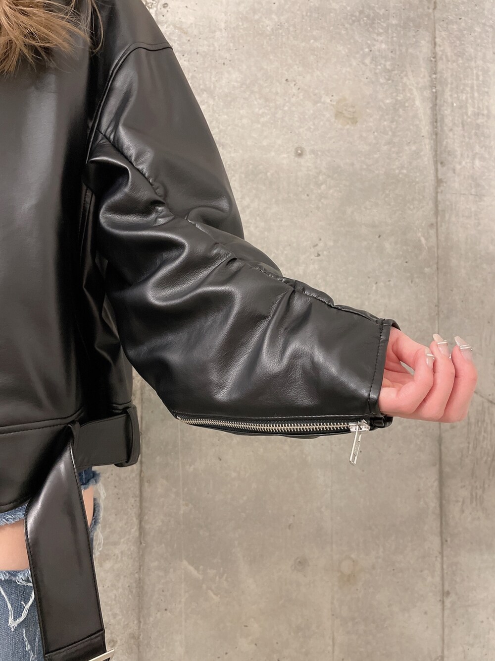 ブラック系のライダースジャケット、ブルー系のデニムパンツ、ホワイト系のスウェットを着用したレディースの冬コーディネートの4枚目の写真