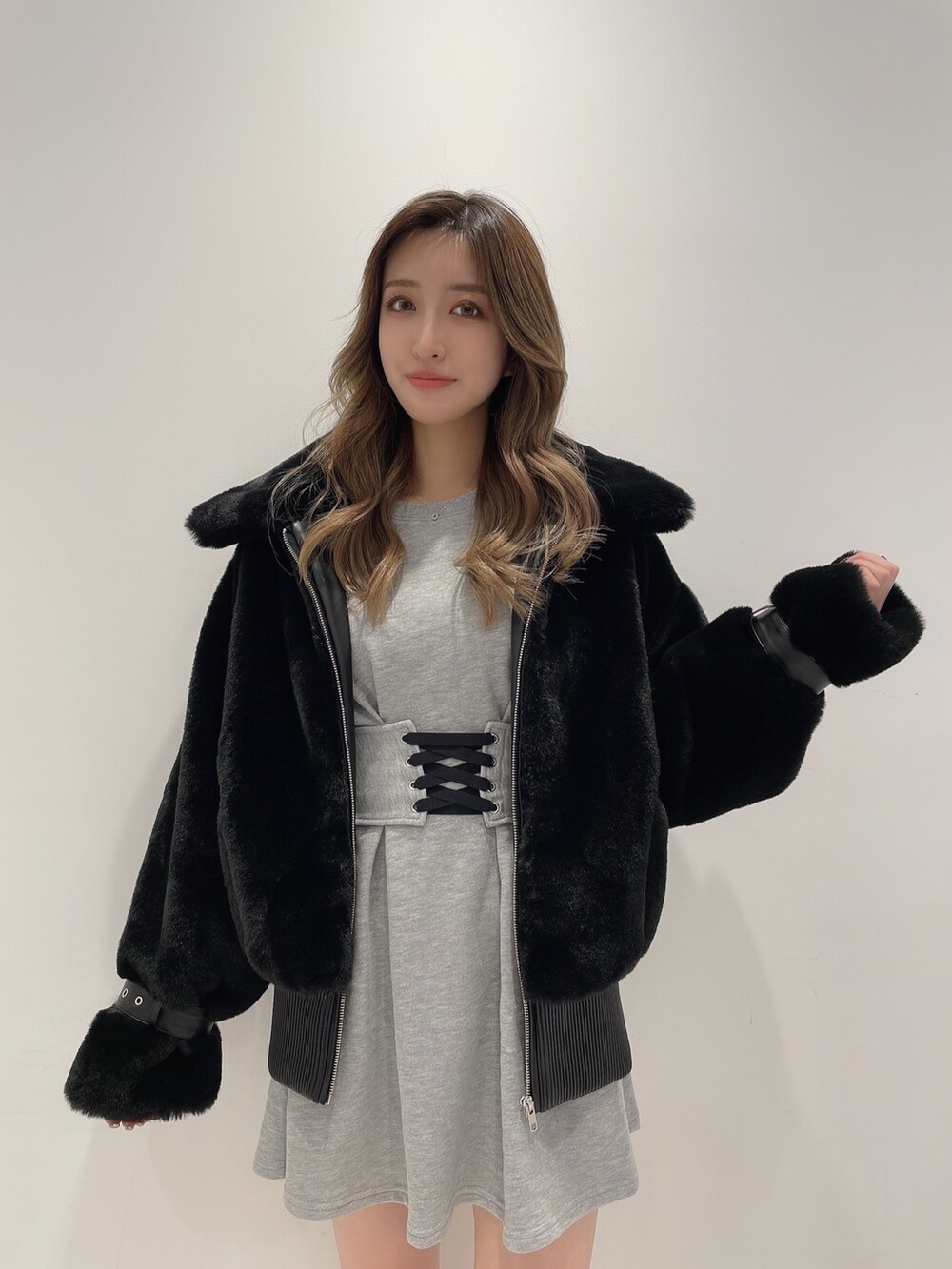 グレー系のワンピース、ブラック系のブーツ、ブラック系のブルゾンを着用したレディースの冬コーディネートの2枚目の写真