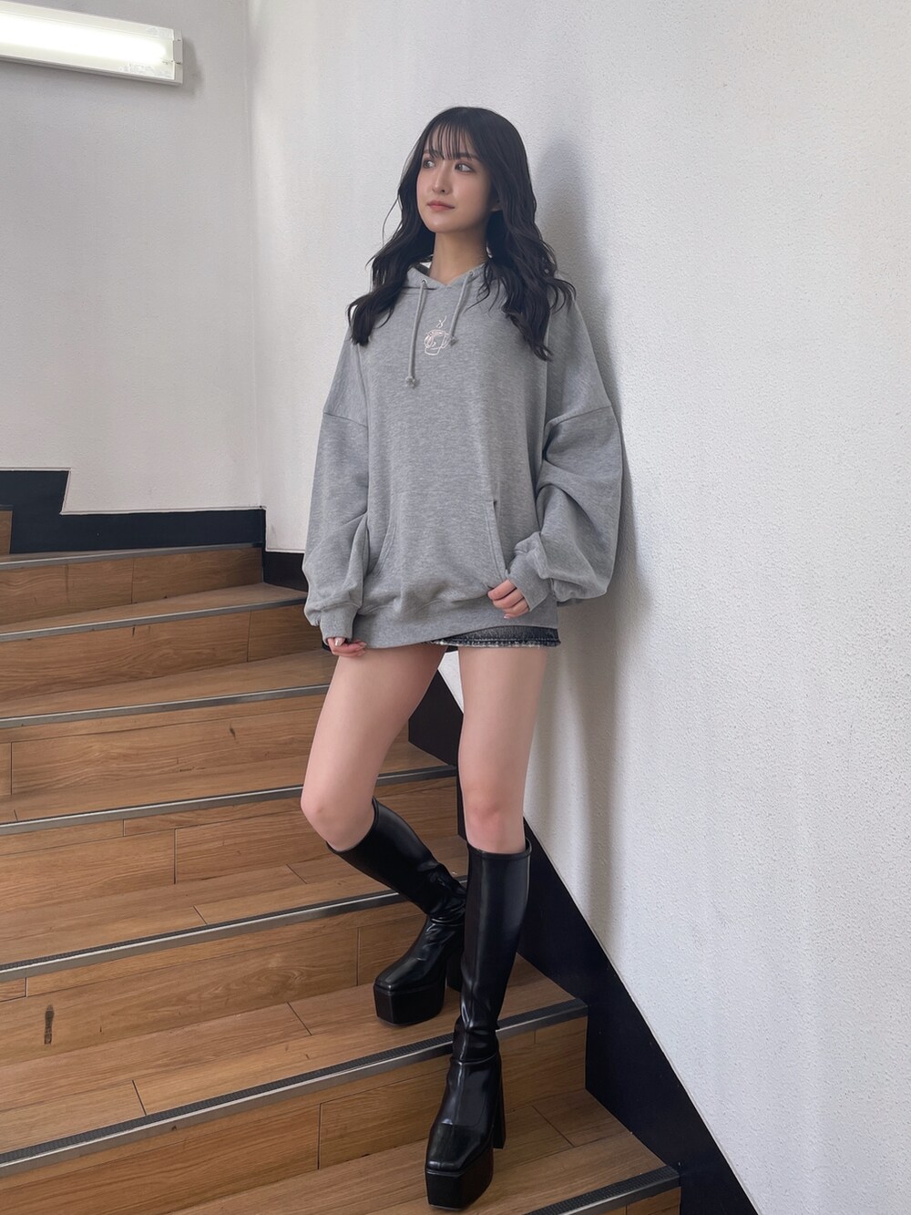 グレー系のスウェット、ブラック系のデニムスカート、ブラック系のブーツを着用したレディースの秋コーディネートの2枚目の写真