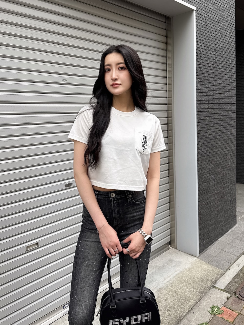 ホワイト系のTシャツ/カットソー、ブラック系のデニムパンツ、ブラック系のボストンバッグを着用したレディースの夏コーディネートの4枚目の写真