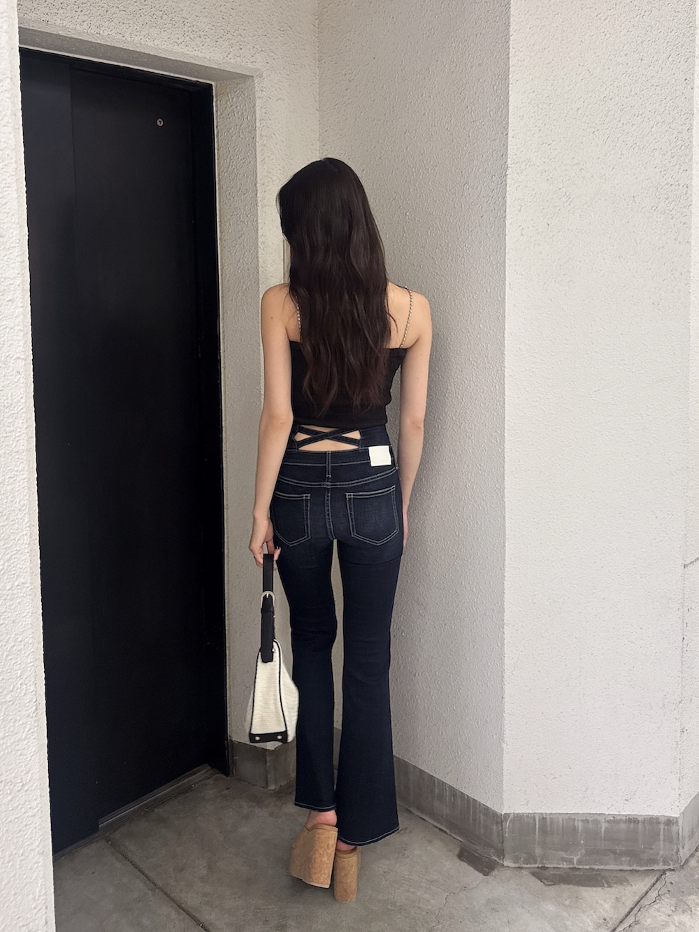 ブラック系のシャツ/ブラウス、ブルー系のデニムパンツ、ホワイト系のハンドバッグを着用したレディースの夏コーディネートの2枚目の写真