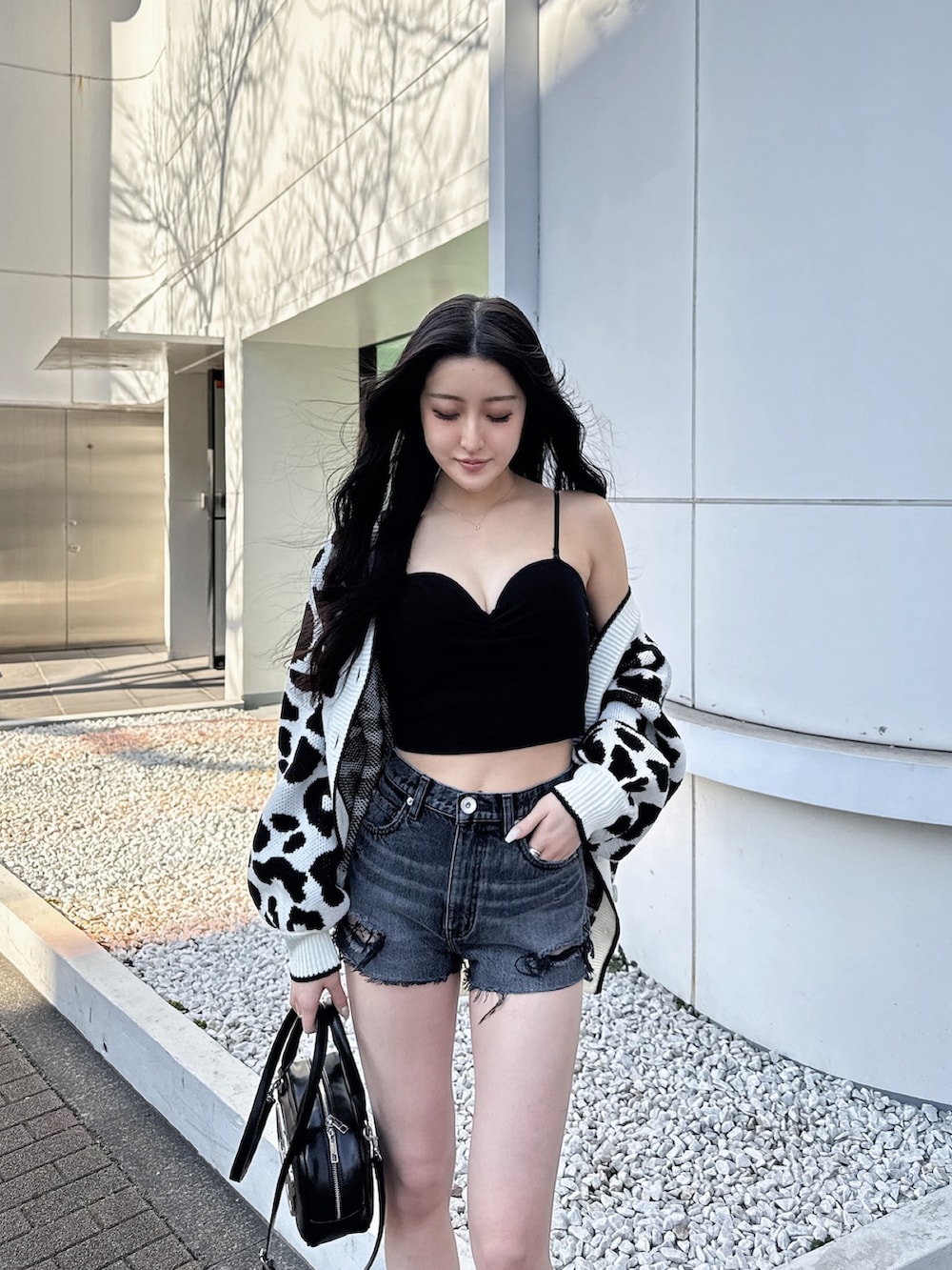 ホワイト系のカーディガン/ボレロ、ブラック系のキャミソール、ブラック系のデニムパンツを着用したレディースの春コーディネートの3枚目の写真