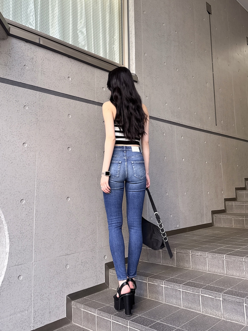 ブラック系のニット/セーター、ブルー系のデニムパンツ、ブラック系のサンダルを着用したレディースの春コーディネートの3枚目の写真