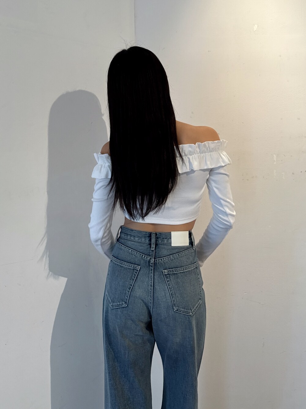 ホワイト系のTシャツ/カットソー、ブルー系のデニムパンツ、ホワイト系のパンプスを着用したレディースの冬コーディネートの4枚目の写真