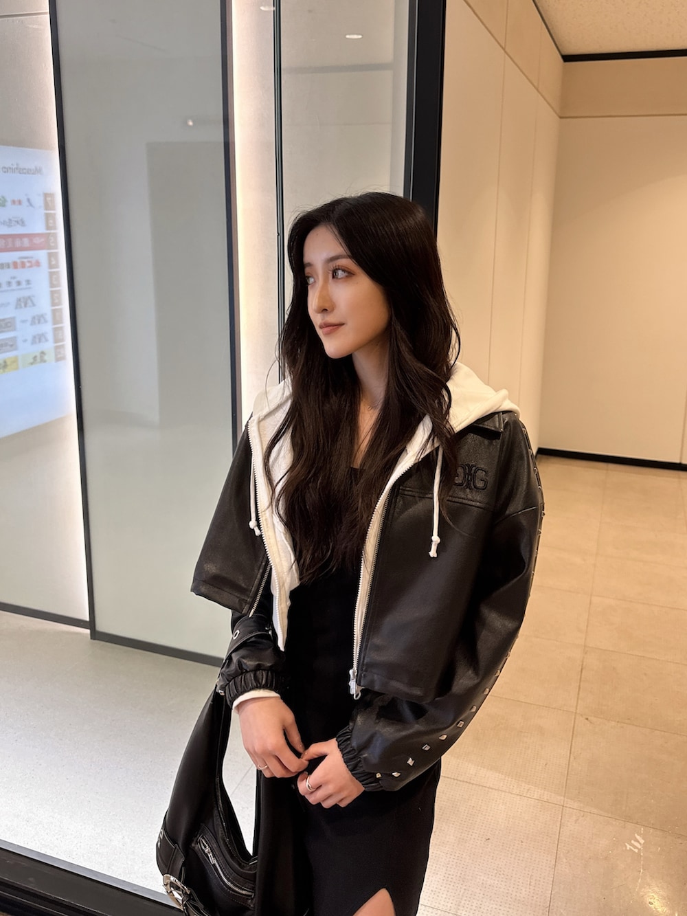 ホワイト系のパーカー、ブラック系のワンピース、ブラック系のライダースジャケットを着用したレディースの春コーディネートの2枚目の写真