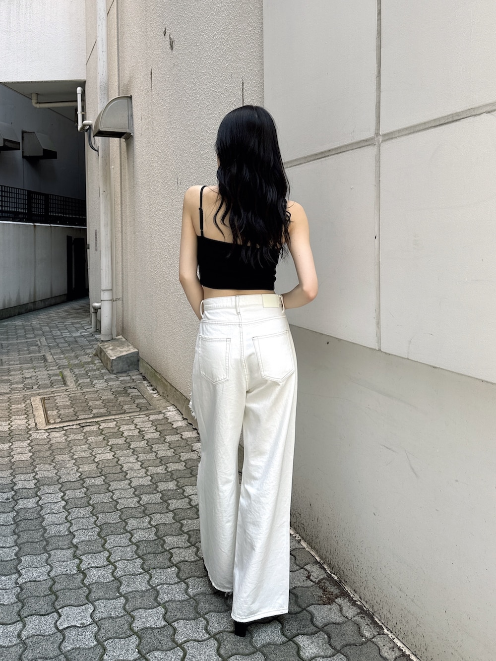 ホワイト系のデニムパンツ、ブラック系のキャミソール、ブラック系のサンダルを着用したレディースの夏コーディネートの4枚目の写真