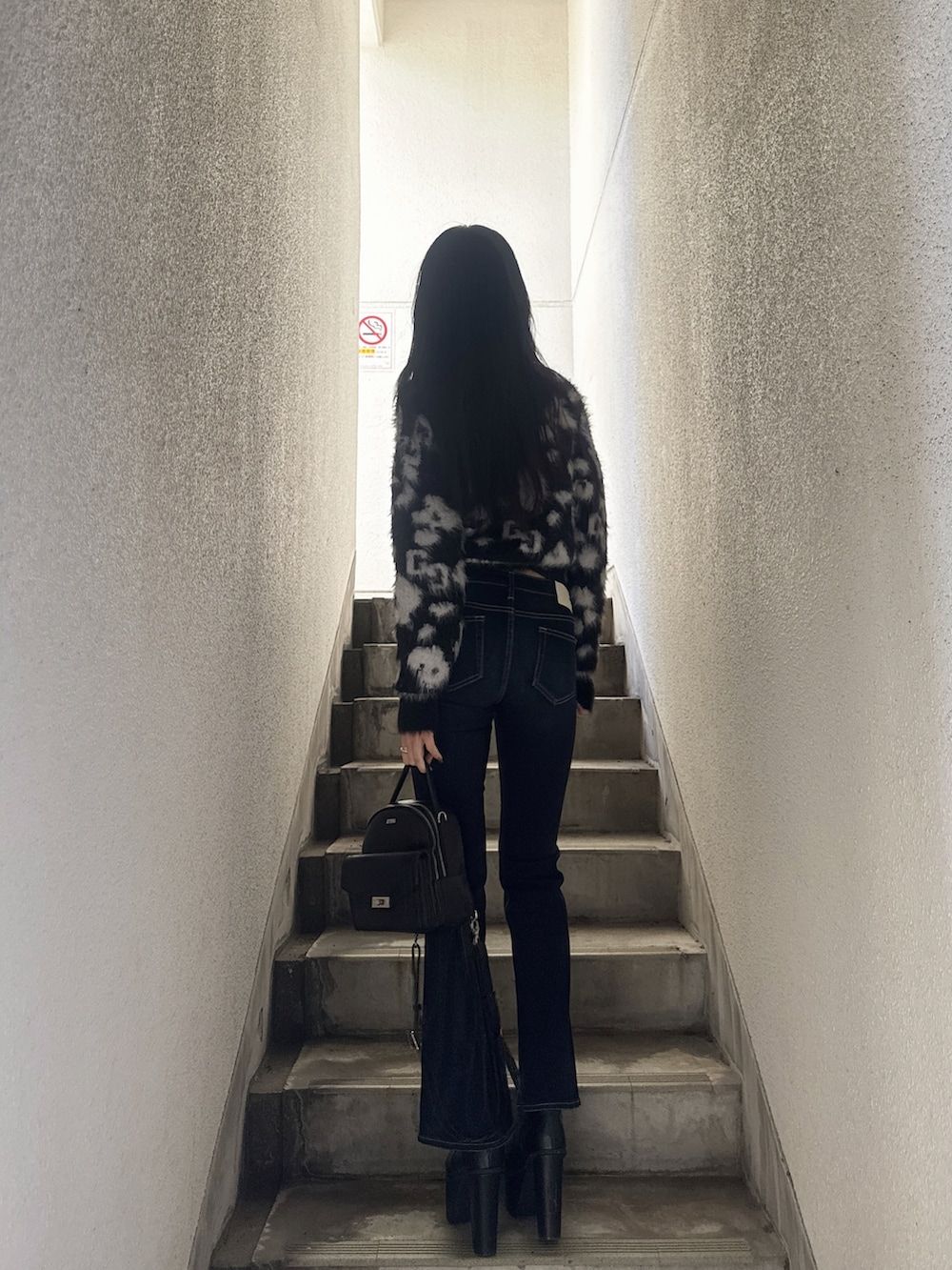 ブルー系のデニムパンツ、ブラック系のニット/セーター、ブラック系のブーツを着用したレディースの冬コーディネートの2枚目の写真