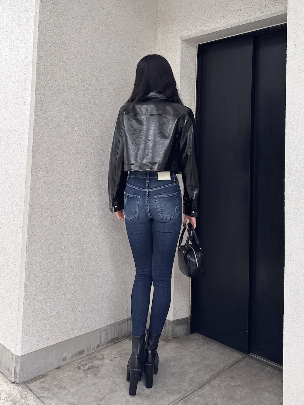 ブラック系のライダースジャケット、ブルー系のデニムパンツ、ブラック系のニット/セーターを着用したレディースの春コーディネートの3枚目の写真