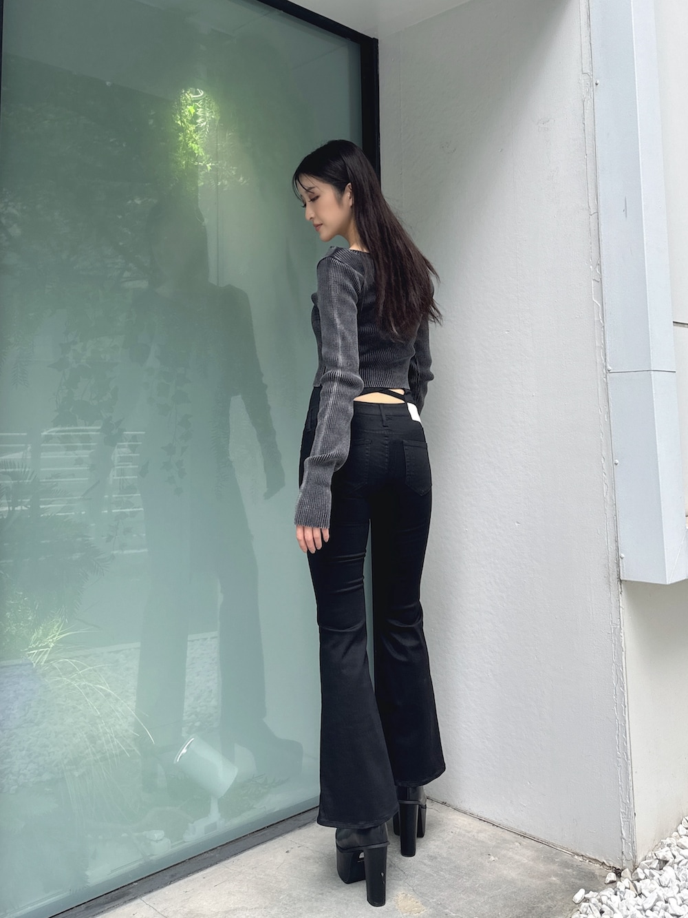 ブラック系のニット/セーター、ブラック系のデニムパンツ、ブラック系のブーツを着用したレディースの秋コーディネートの2枚目の写真