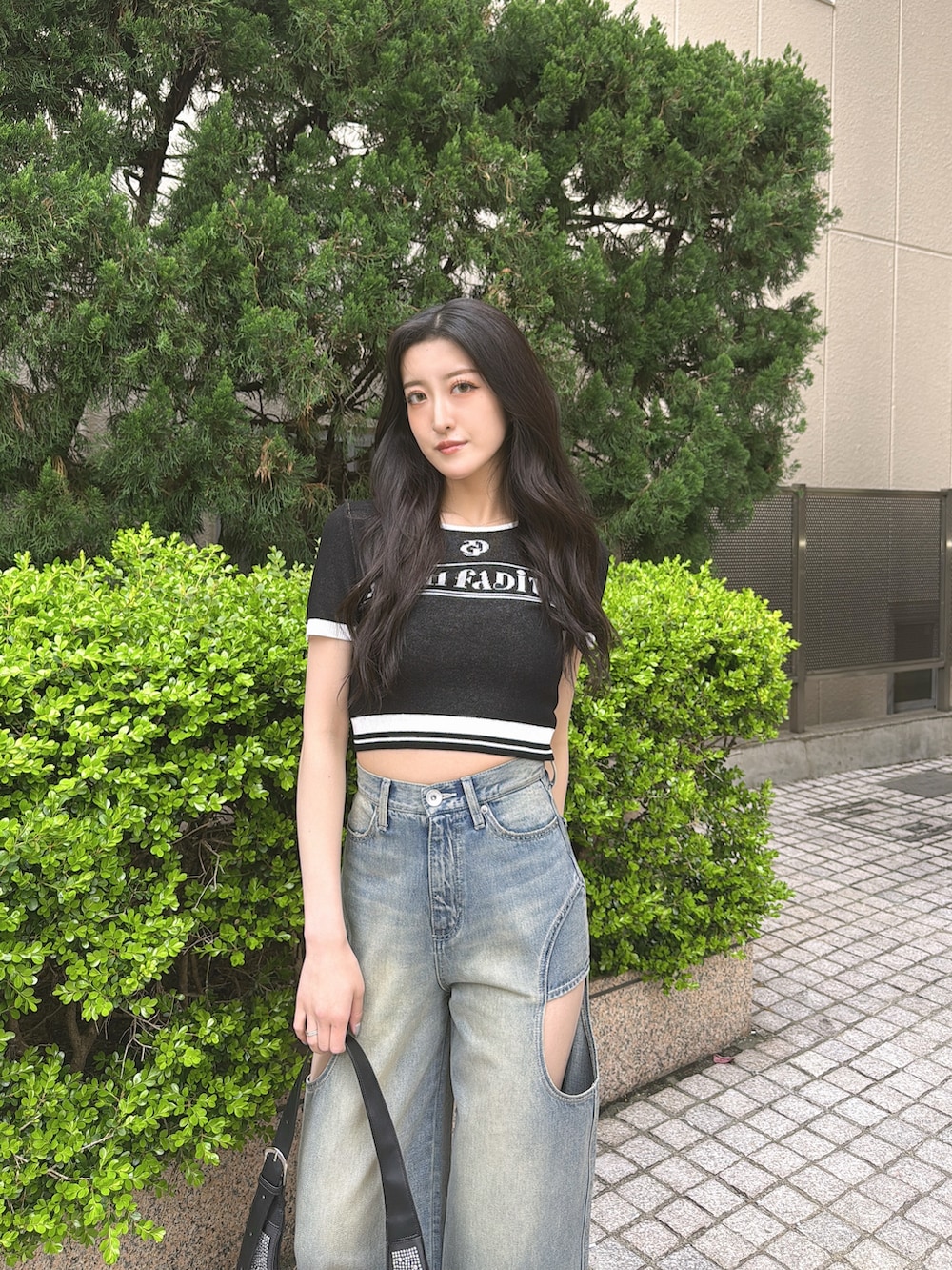 ブラック系のニット/セーター、ブルー系のデニムパンツ、ブラック系のパンプスを着用したレディースの春コーディネートの2枚目の写真