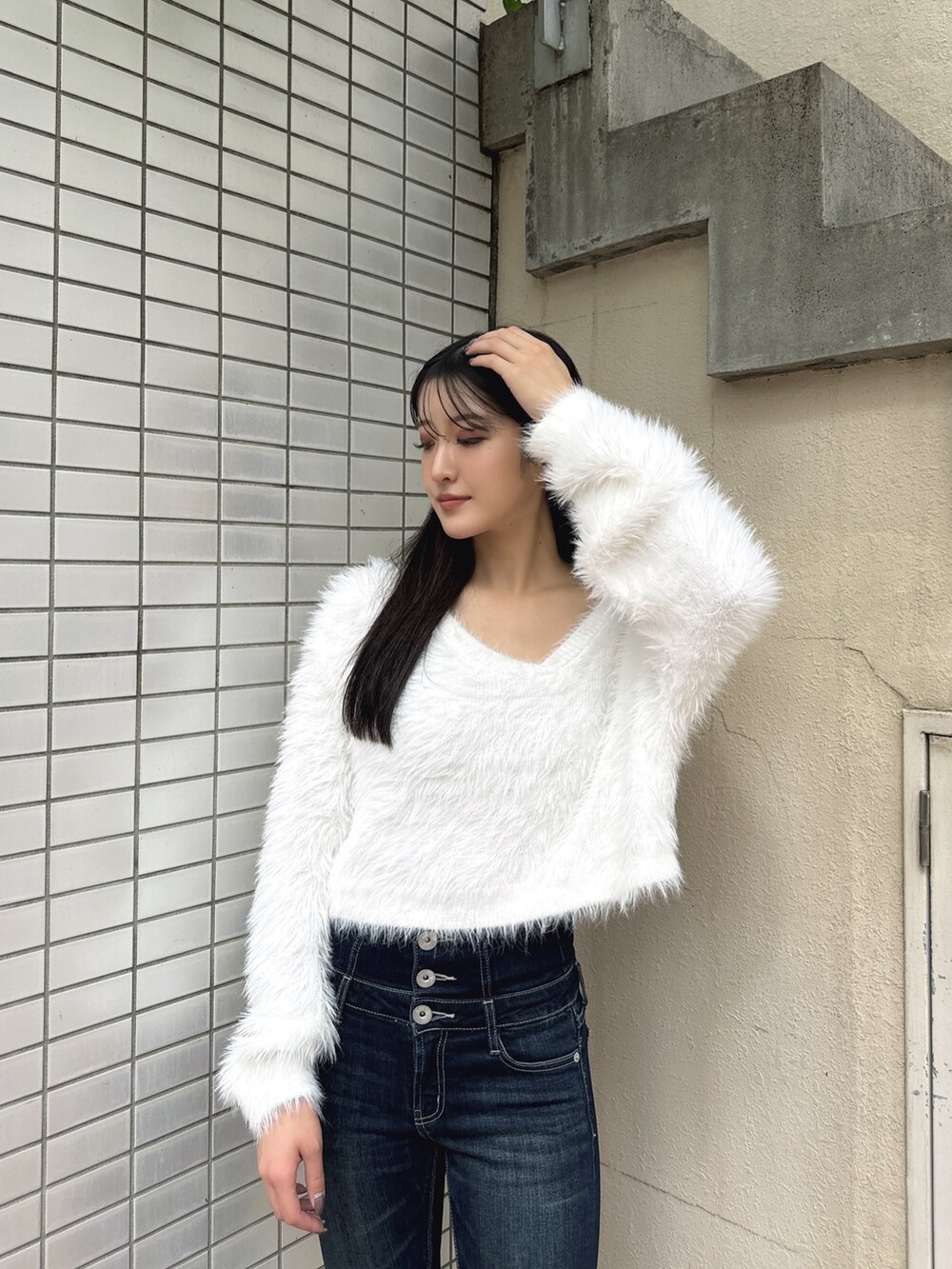 ホワイト系のニット/セーター、ブルー系のデニムパンツ、ブラック系のパンプスを着用したレディースの冬コーディネートの3枚目の写真