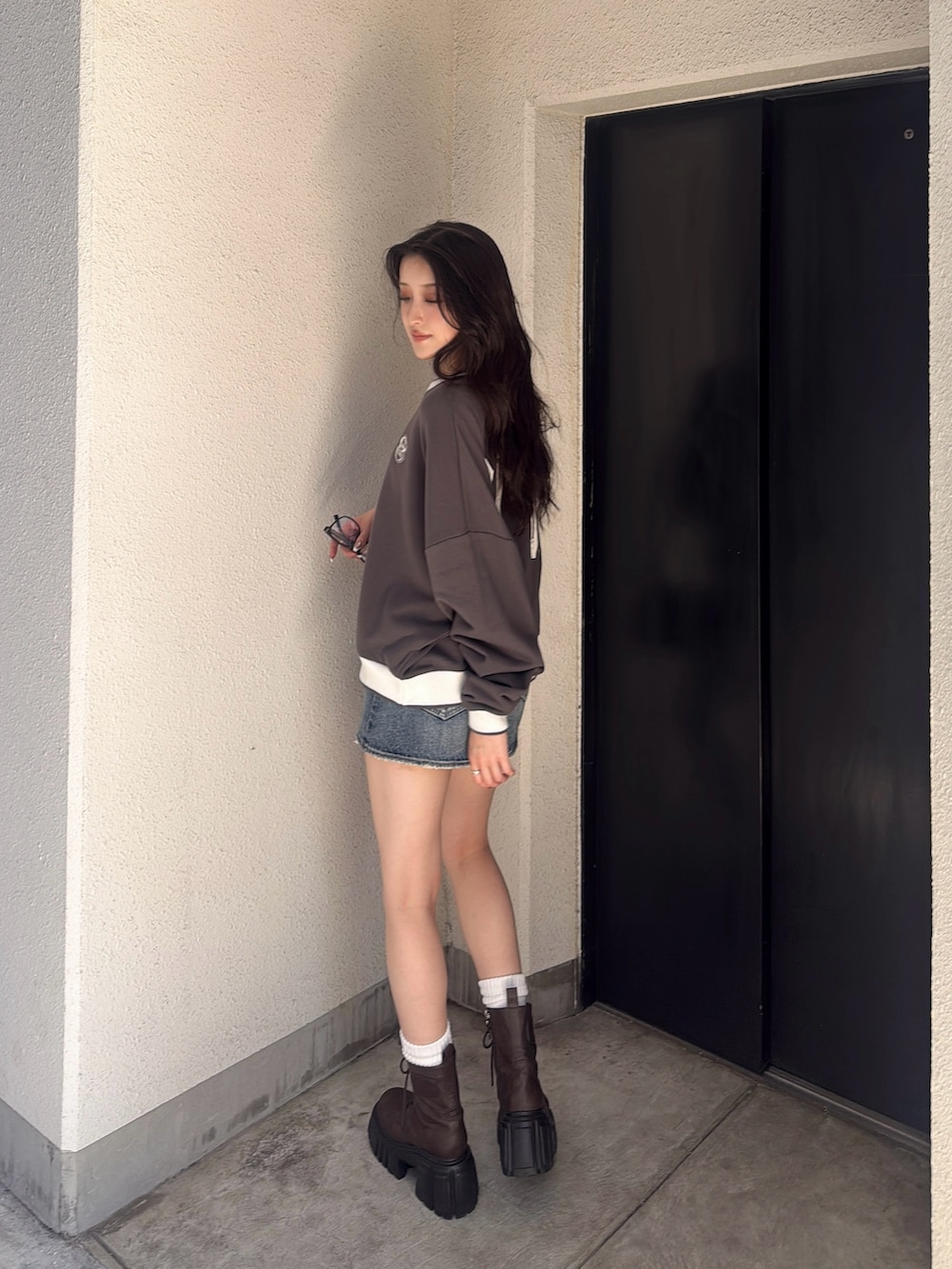 グレー系のスウェット、ブルー系のデニムスカート、ブラック系のハンドバッグを着用したレディースの秋コーディネートの3枚目の写真