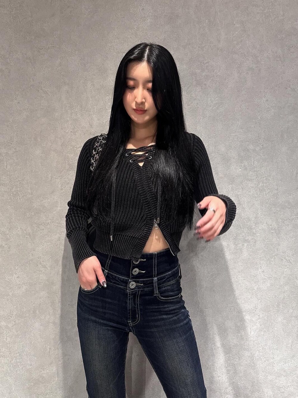 ブラック系のニット/セーター、ブルー系のデニムパンツ、ブラック系のブーツを着用したレディースの秋コーディネートの2枚目の写真