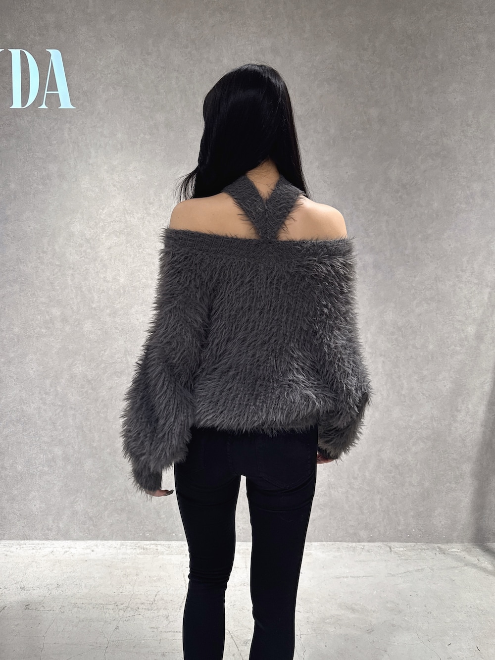 グレー系のニット/セーター、ブラック系のデニムパンツ、ブラック系のブーツを着用したレディースの秋コーディネートの6枚目の写真