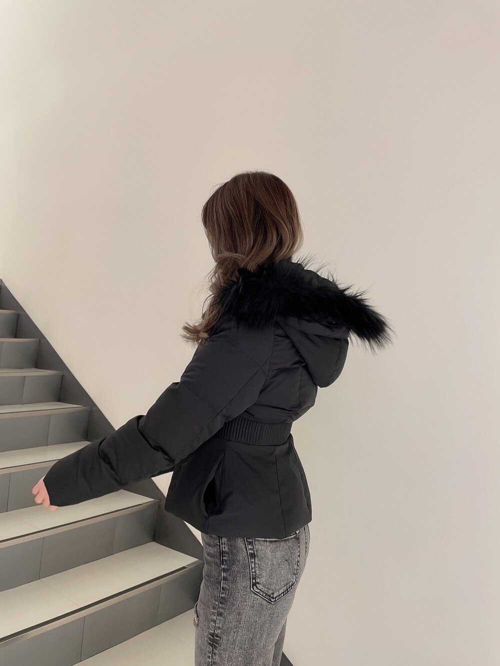 ブラック系のデニムパンツ、ホワイト系のパンプス、ブラック系のその他アウターを着用したレディースの冬コーディネートの4枚目の写真