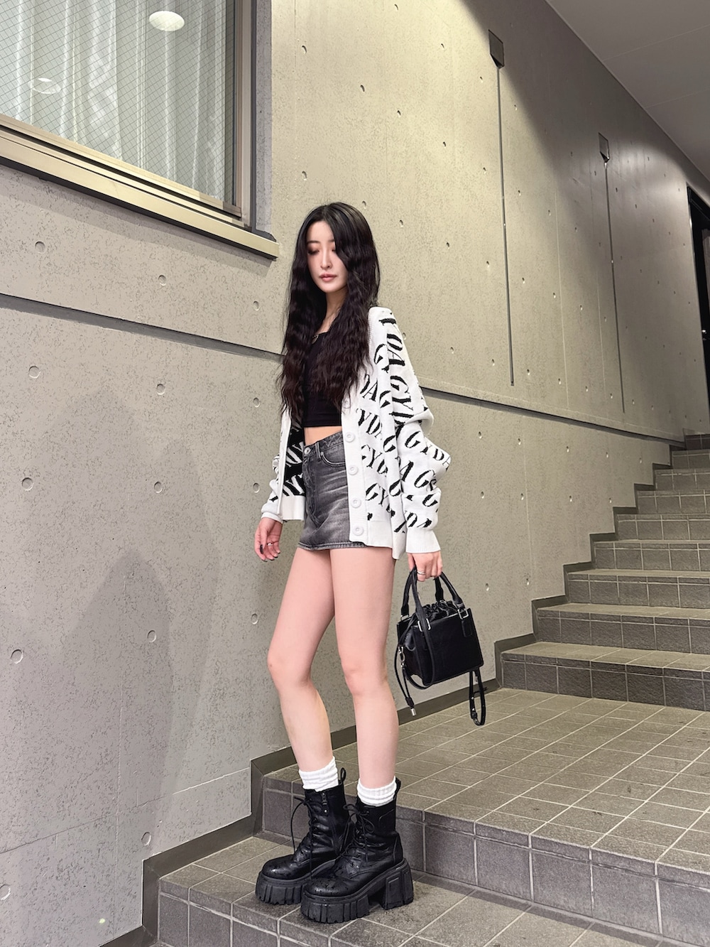 ホワイト系のカーディガン/ボレロ、ブラック系のTシャツ/カットソー、ブラック系のデニムスカートを着用したレディースの春コーディネートの3枚目の写真