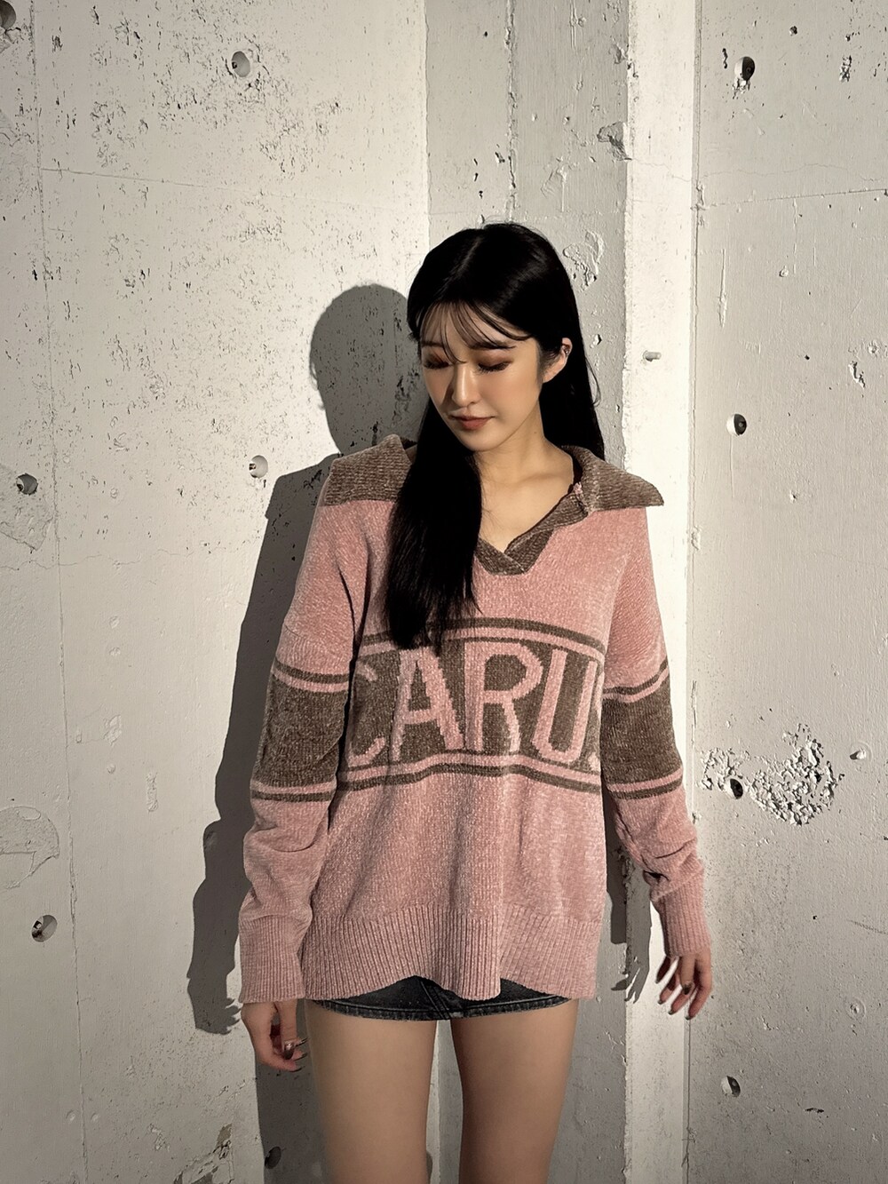 ピンク系のニット/セーター、ブラック系のデニムスカート、ブラック系のブーツを着用したレディースの秋コーディネートの2枚目の写真