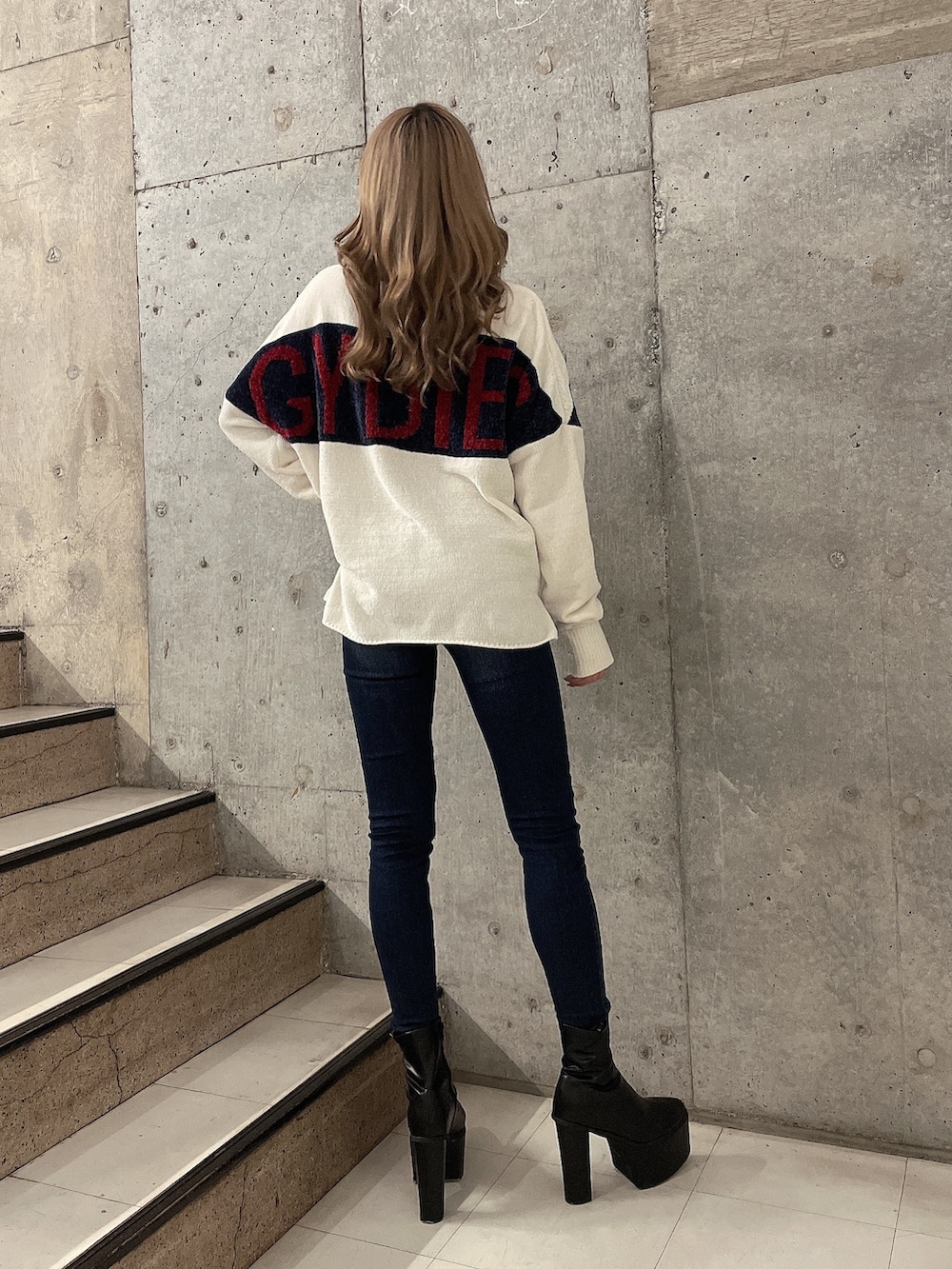 ホワイト系のニット/セーター、ブルー系のデニムパンツ、ブラック系のブーツを着用したレディースの秋コーディネートの2枚目の写真