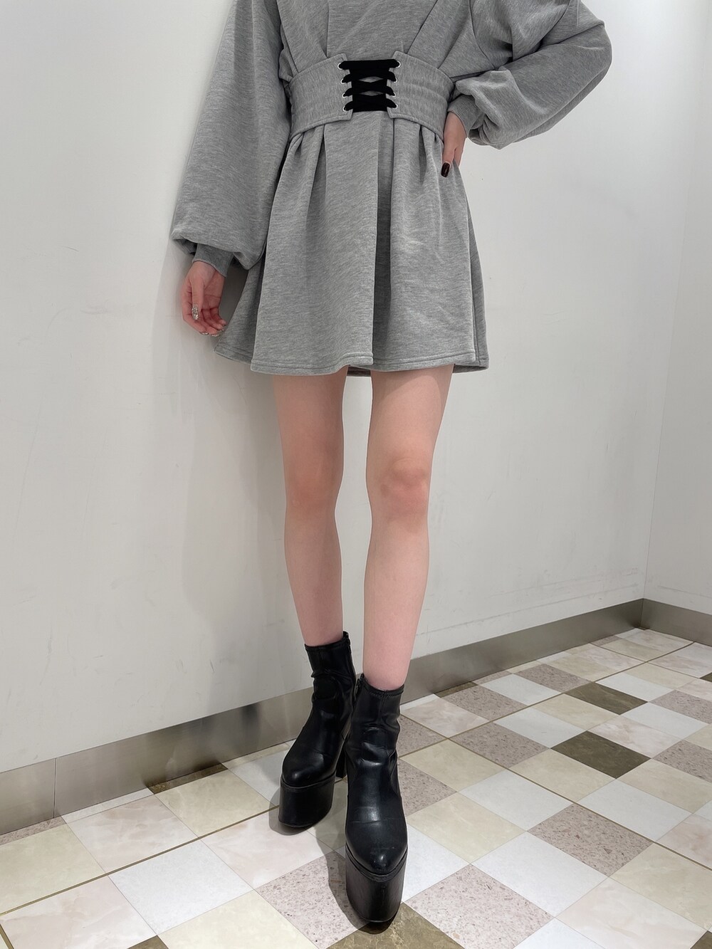 グレー系のワンピース、ブラック系のデニムパンツ、ブラック系のブーツを着用したレディースの冬コーディネートの5枚目の写真