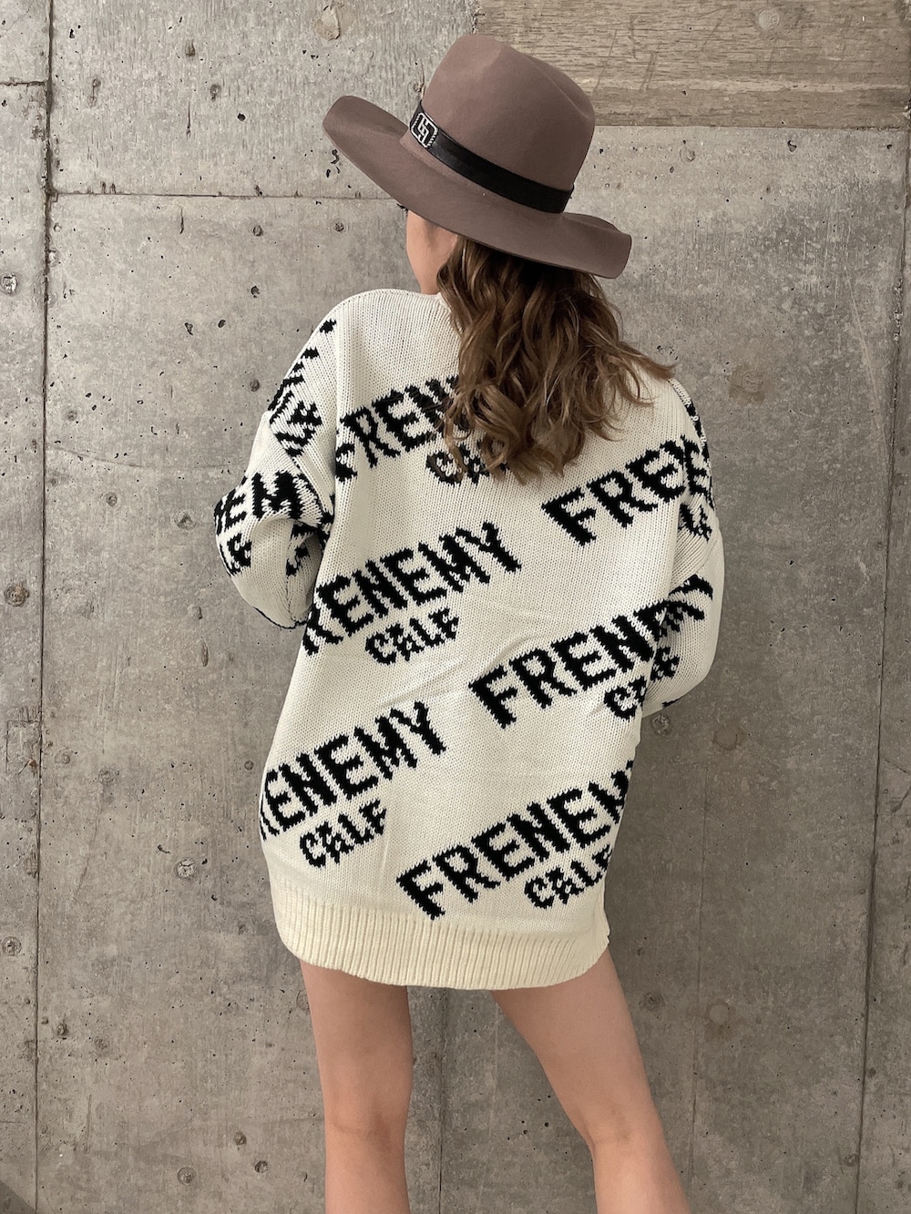 ホワイト系のニット/セーター、ブラック系のブーツ、ブラック系のデニムパンツを着用したレディースの秋コーディネートの4枚目の写真